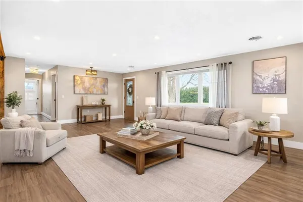 a spacious bedroom with a bed a chandelier with dresser and mirror