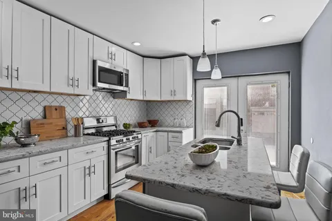 a kitchen with stainless steel appliances granite countertop a sink a stove and a wooden floors