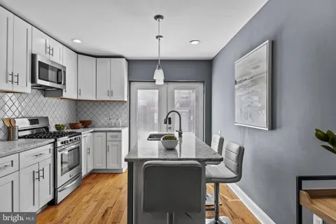 a kitchen with stainless steel appliances granite countertop a stove top oven a sink dishwasher and white cabinets with wooden floor