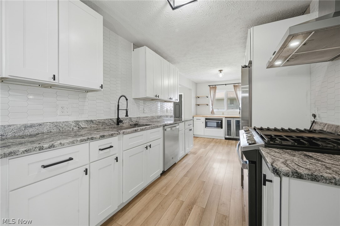 8160 Joyce Road Broadview Heights, OH 44147 - Photo 13 of 45 Kitchen featuring white shaker cabinetry, granite countertops, stainless steel appliances, wood-finish flooring, and a white picket tile backsplash