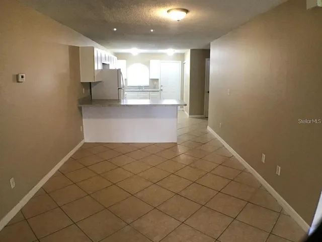 a view of kitchen and empty room with wooden floor