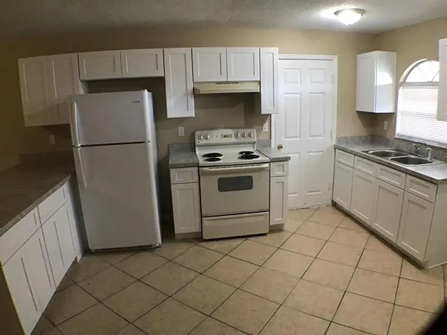 a kitchen with granite countertop a sink stove and refrigerator