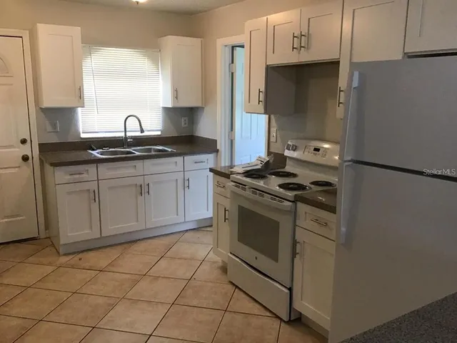 a kitchen with granite countertop a sink stove and cabinets