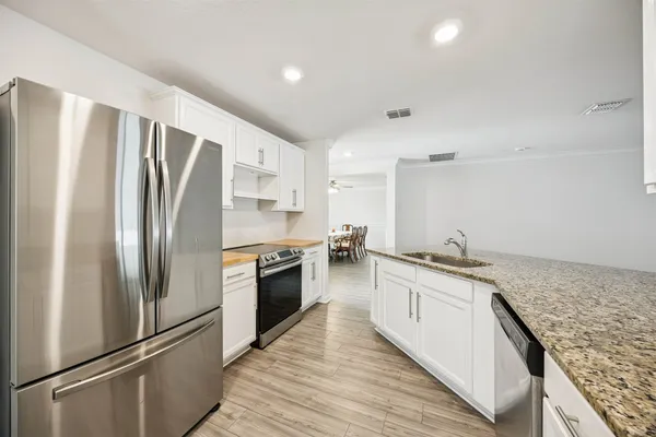 a large kitchen with stainless steel appliances granite countertop a refrigerator and a stove top oven