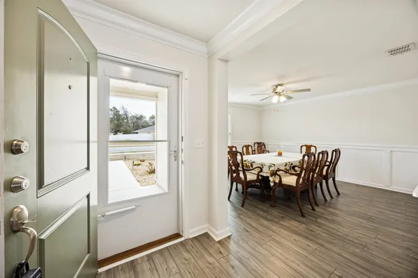 a kitchen with stainless steel appliances a stove top oven a refrigerator a dining table and chairs with wooden floor