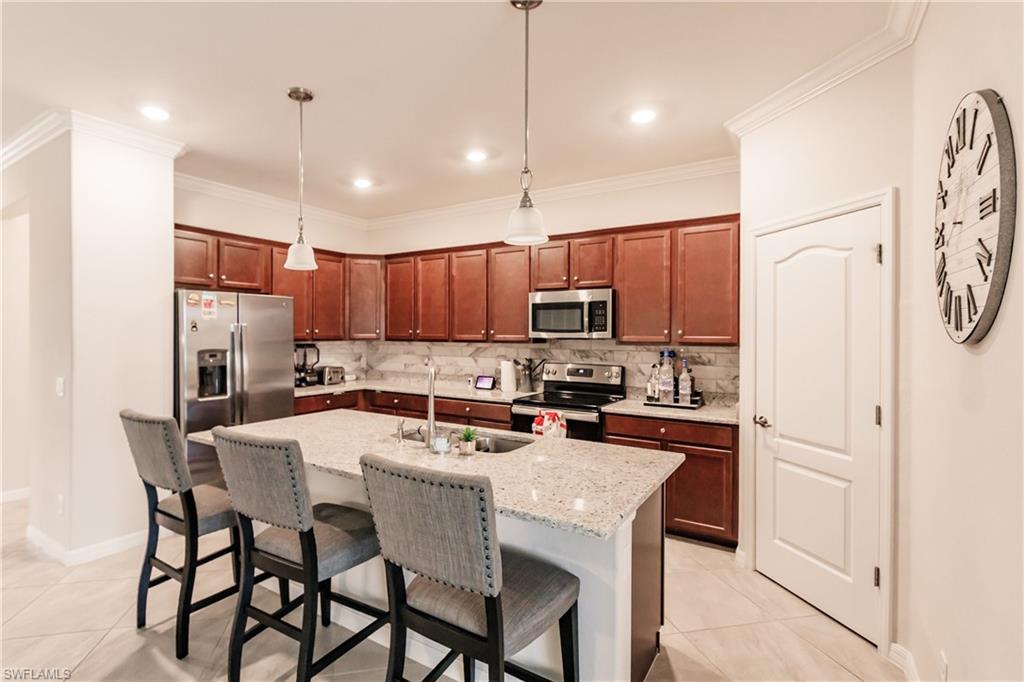 2247 Dancy Street Naples, FL 34120 - Photo 12 of 32 a kitchen with kitchen island granite countertop a dining table chairs refrigerator and microwave