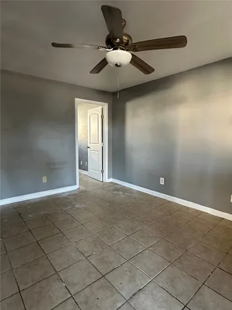 a view of an empty room and chandelier fan
