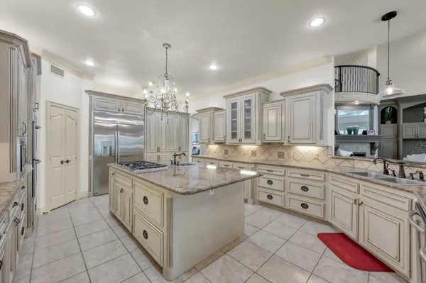 a large kitchen with kitchen island a chandelier stainless steel appliances a sink and cabinets