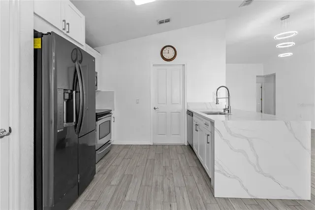 a kitchen with a refrigerator a stove top oven and cabinets
