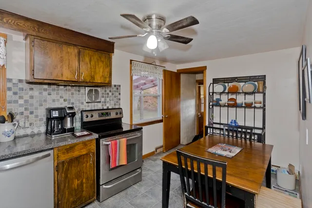 a open kitchen with stainless steel appliances granite countertop a stove a refrigerator a sink dishwasher a dining table and chairs with wooden floor