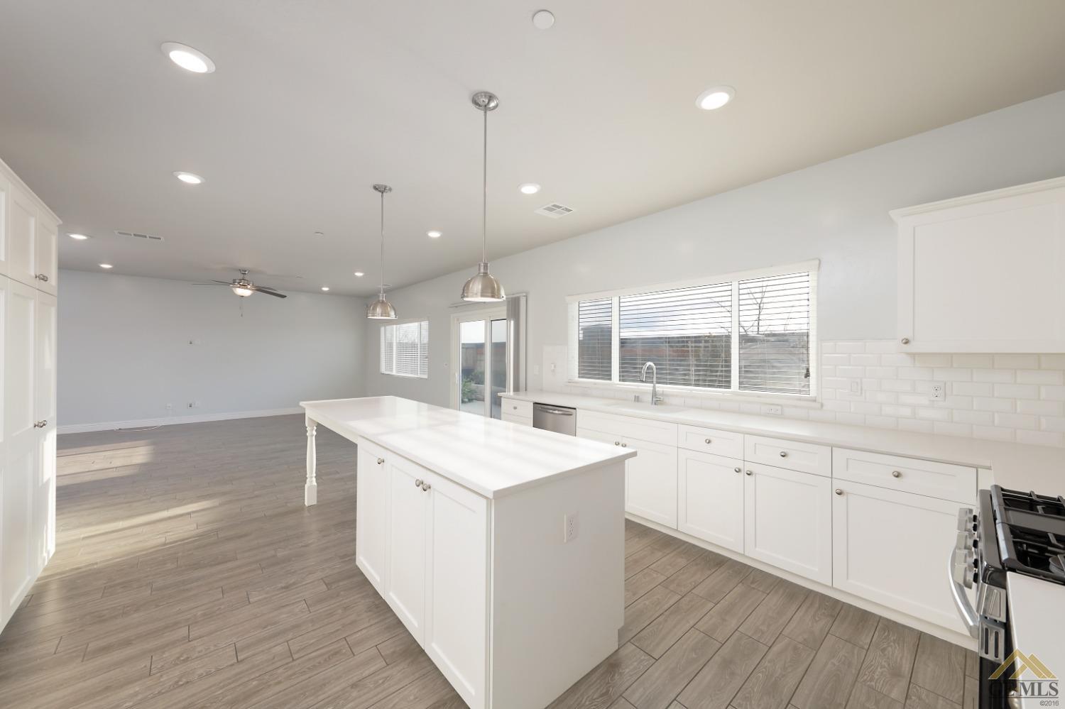 Undisclosed Address Shafter, CA 93263 - Photo 30 of 36 a large kitchen with kitchen island a sink a center island and wooden floor