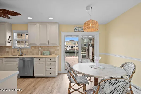 a kitchen with stainless steel appliances granite countertop a stove a sink dishwasher a refrigerator and white cabinets with wooden floor
