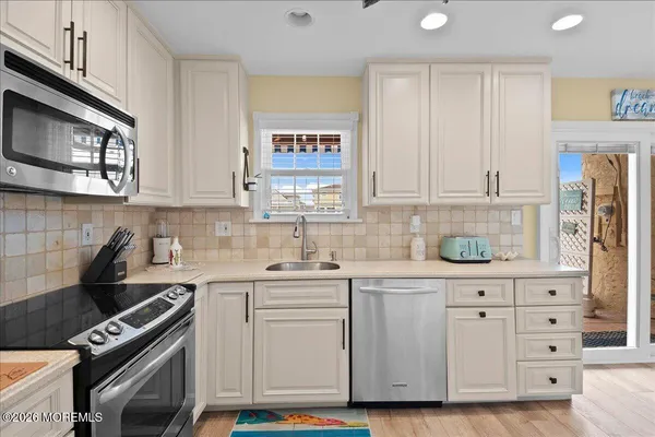 a kitchen with stainless steel appliances granite countertop a refrigerator a stove top oven a sink dishwasher and a dining table with wooden floor