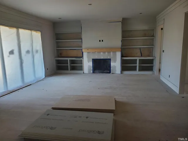 an empty room with a fireplace and cabinet