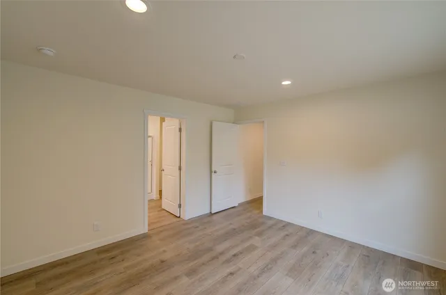 a view of an empty room with wooden floor and closet