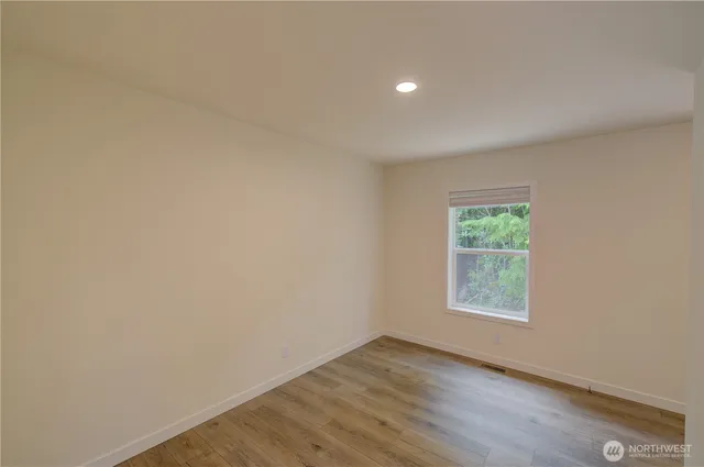 an empty room with wooden floor and window