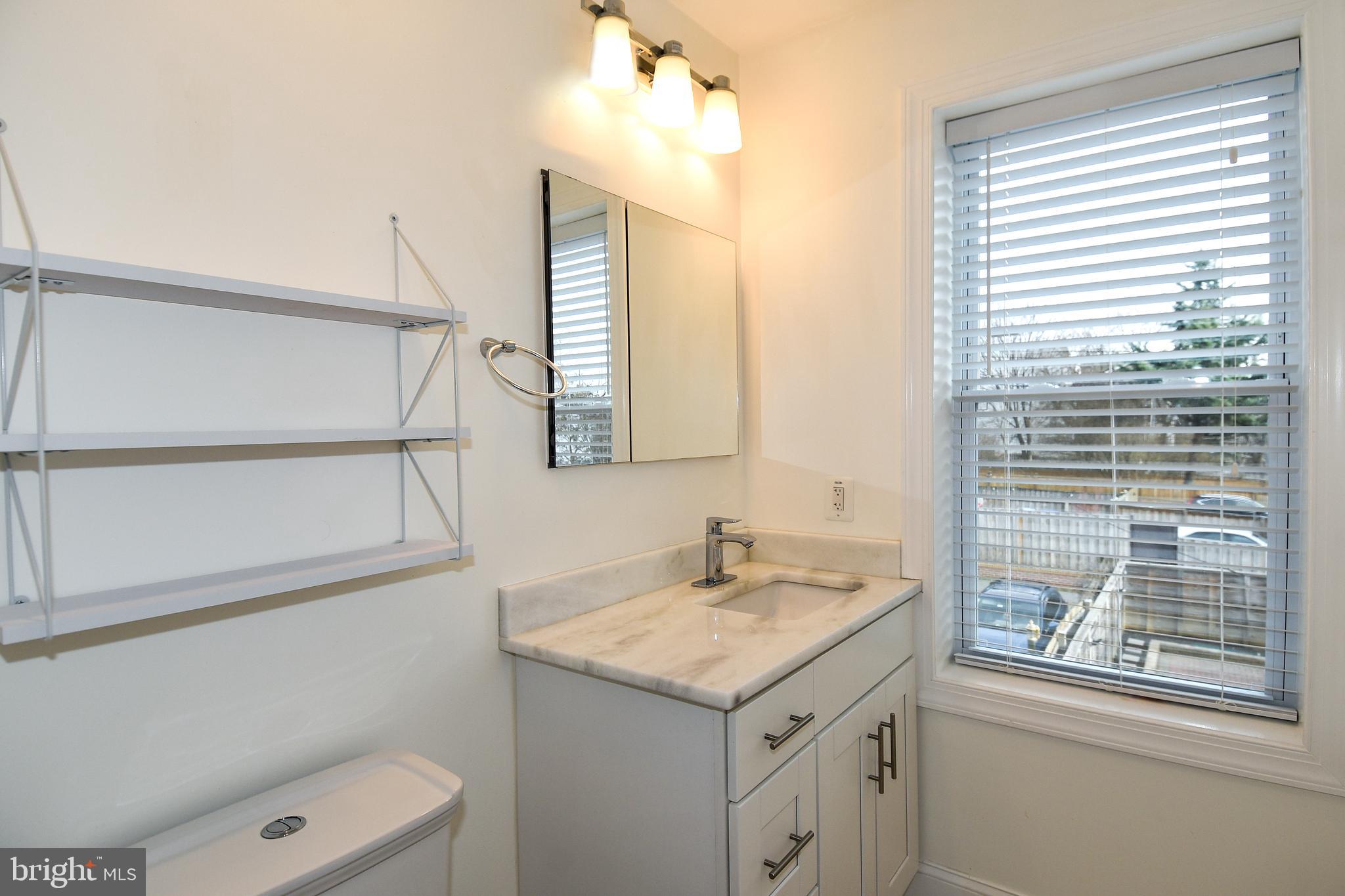 1117 Montello Avenue Northeast Washington, DC 20002 - Photo 23 of 64 a bathroom with a granite countertop sink a toilet and a mirror