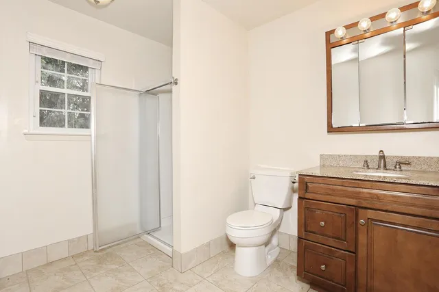 a bathroom with a granite countertop toilet sink and mirror