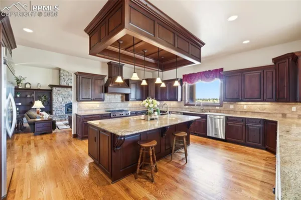a dining room with stainless steel appliances kitchen island granite countertop a table chairs and a view of living room