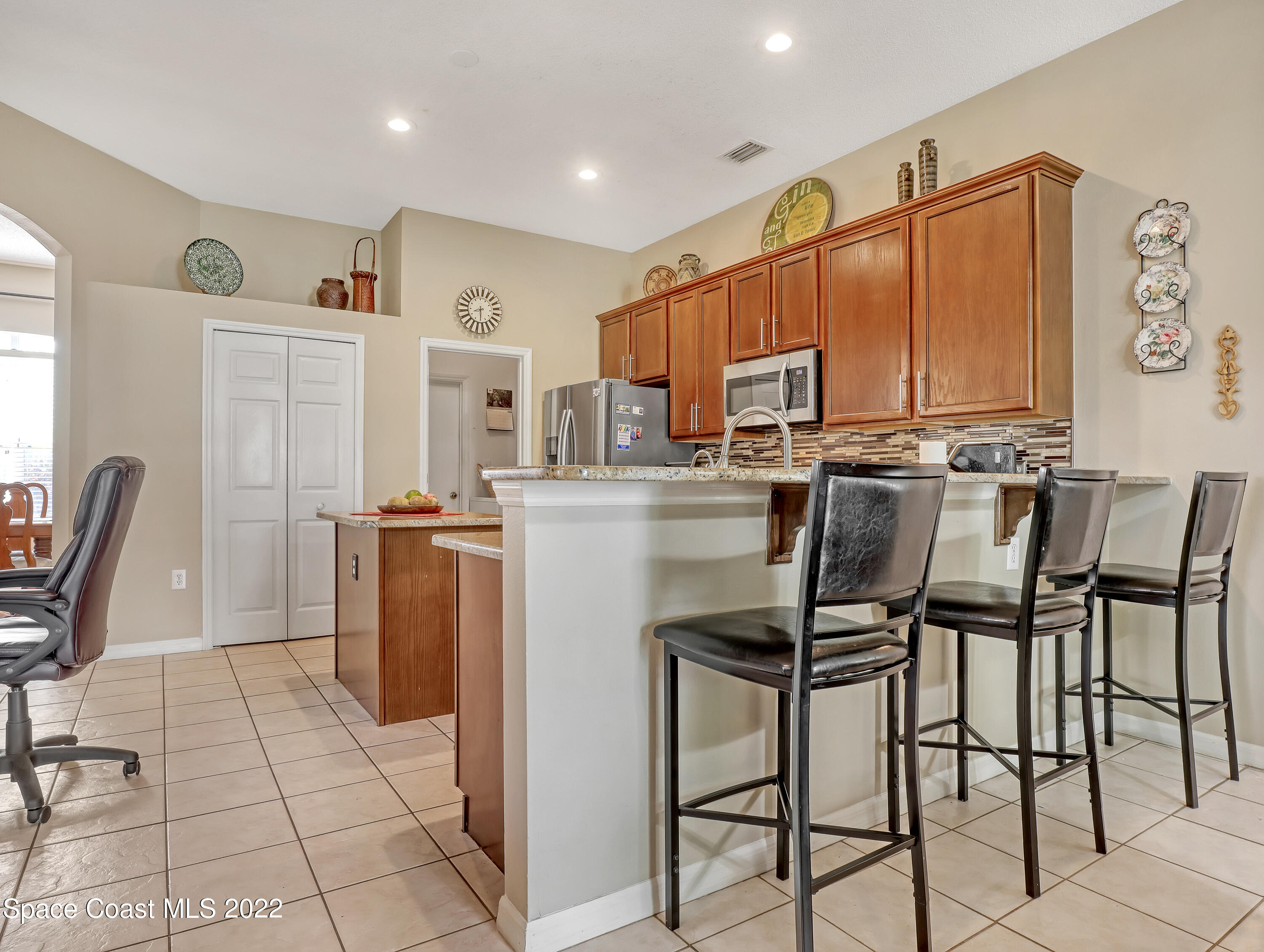755 Raleigh Road Southeast Palm Bay, FL 32909 - Photo 12 of 36 a kitchen with stainless steel appliances kitchen island granite countertop a table chairs and a refrigerator