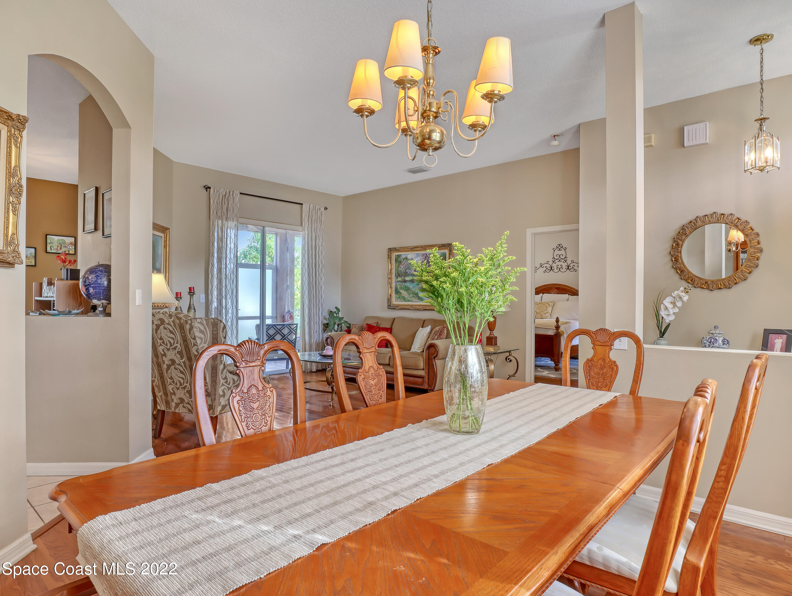 755 Raleigh Road Southeast Palm Bay, FL 32909 - Photo 10 of 36 a dining room with wooden floor a chandelier a wooden table and chairs