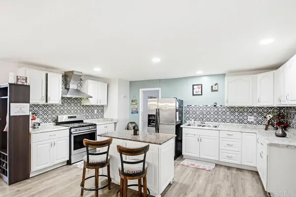 a kitchen with stainless steel appliances kitchen island granite countertop a stove and white cabinets