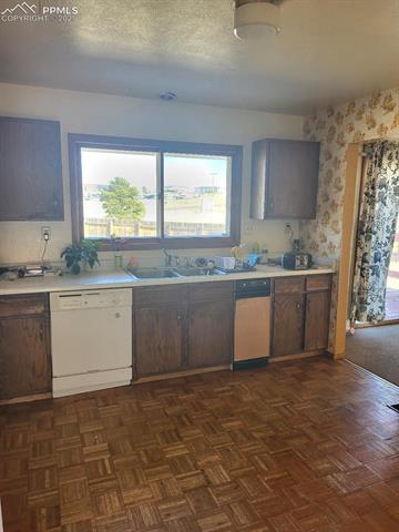 1215 Old Ranch Road Colorado Springs, CO 80920 - Photo 6 of 15 Kitchen with sink, dishwasher, dark parquet flooring, and dark brown cabinetry