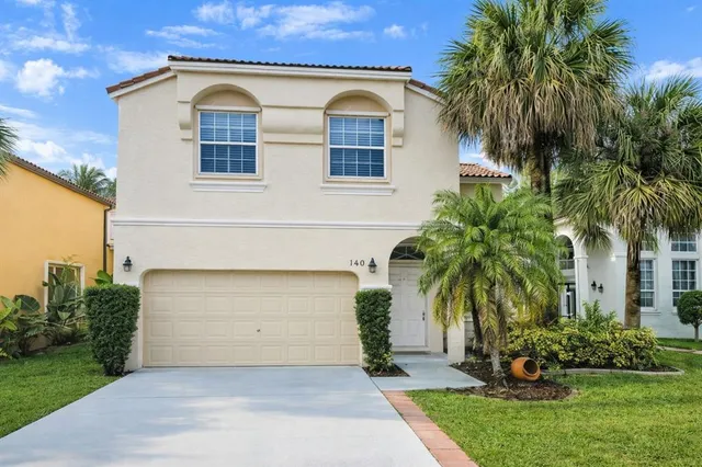 a front view of a house with a yard and palm trees