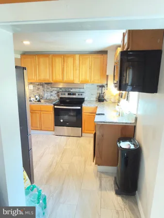 a kitchen with stainless steel appliances kitchen island granite countertop a sink and a black refrigerator