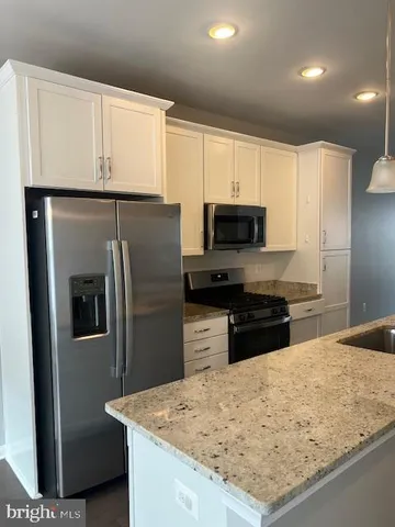 a kitchen with granite countertop a refrigerator stove and sink