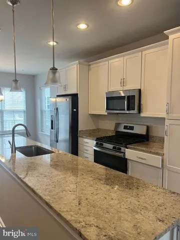 a kitchen with stainless steel appliances granite countertop a sink a stove a refrigerator a center island with wooden cabinets and floor