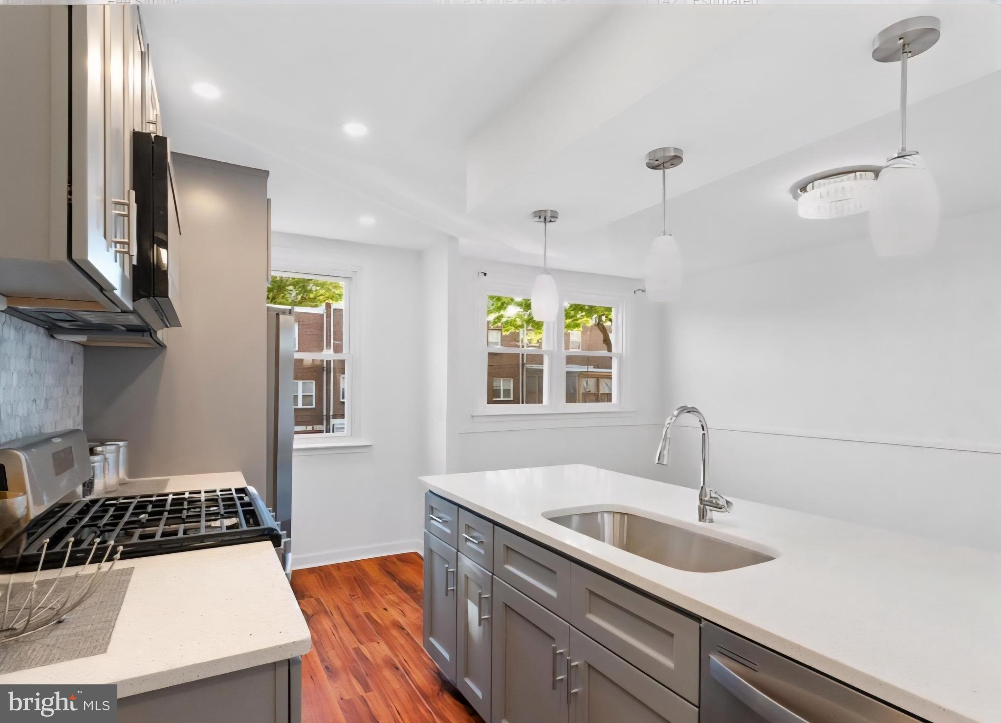 8332 Forrest Avenue Philadelphia, PA 19150 - Photo 8 of 19 a kitchen with a sink stove and wooden floor
