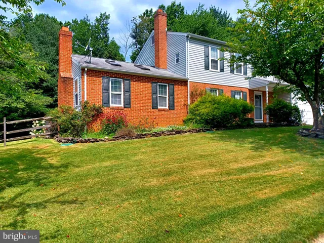a view of a house with a yard and a large tree
