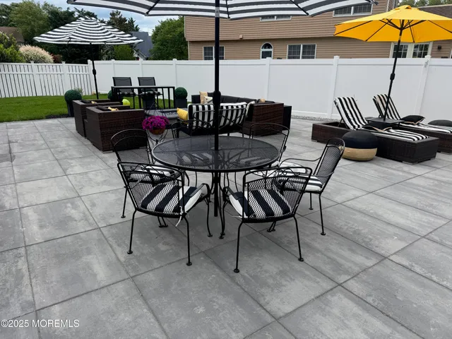 a kitchen view with stainless steel appliances granite countertop a stove a refrigerator a oven a dining table and chairs with wooden floor