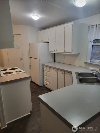 a kitchen with a sink a stove a refrigerator and white cabinets