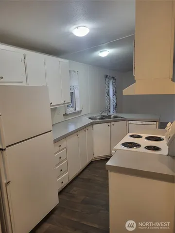 a kitchen with a sink a stove a refrigerator and white cabinets