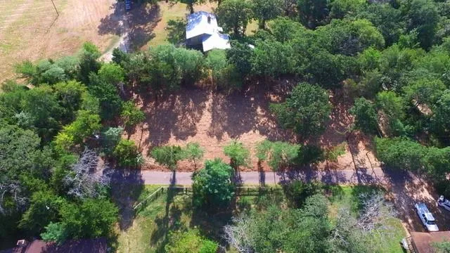 an aerial view of residential house with outdoor space and trees all around