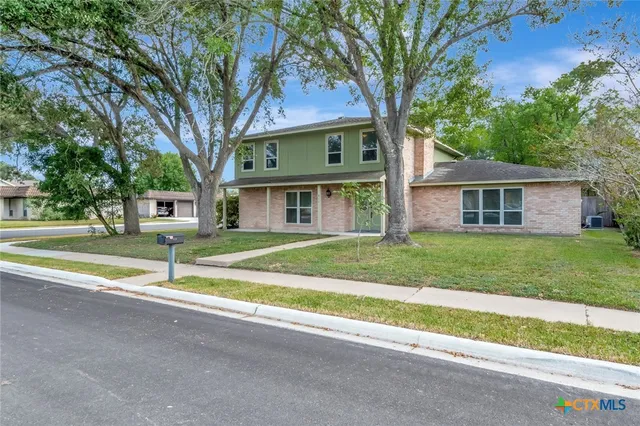 a view of a house with a big yard and large trees