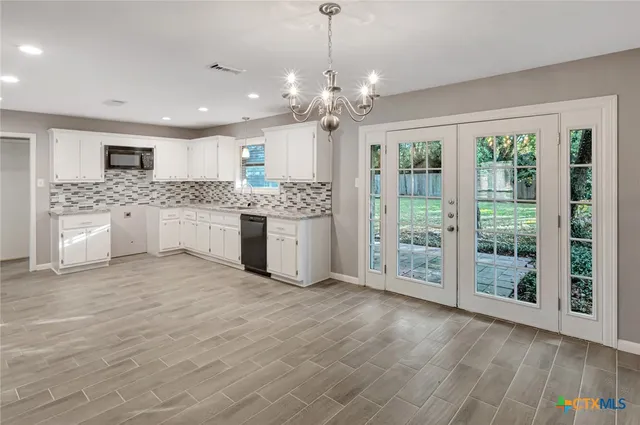 a large white kitchen with stainless steel appliances kitchen island granite countertop a large counter top and a stove top oven