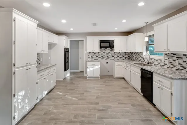 a kitchen with stainless steel appliances granite countertop a sink and cabinets with wooden floor