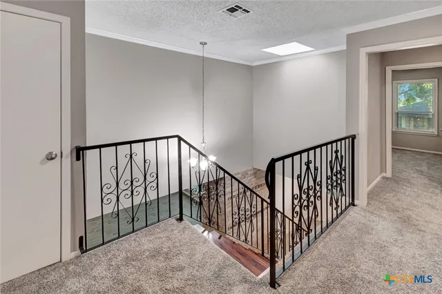 a view of an empty room and chandelier fan