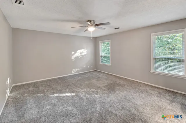 an empty room with a window and a fan