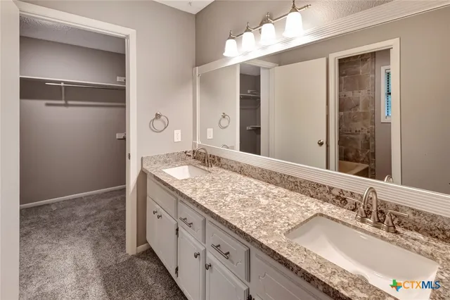 a bathroom with a granite countertop sink a mirror and a shower