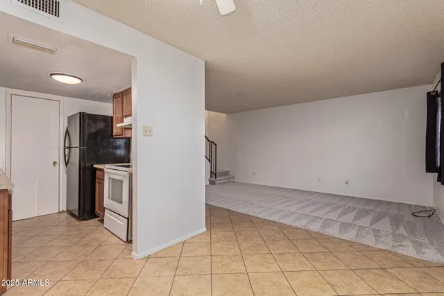 a view of a refrigerator in kitchen and empty room