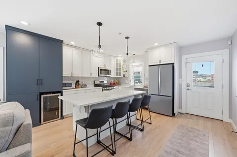a kitchen with kitchen island a refrigerator a stove a sink and white cabinets
