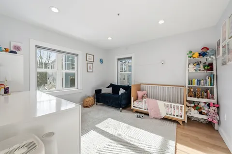 a bedroom with a baby bed couch and a window