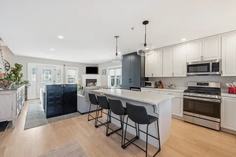 a kitchen with stainless steel appliances a stove a sink dishwasher a refrigerator and a dining table with wooden floor