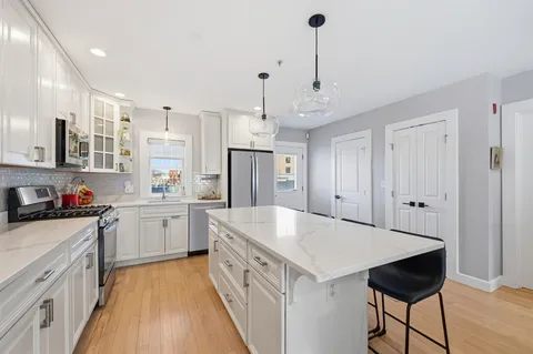 a kitchen with kitchen island a stove a sink a refrigerator and cabinets