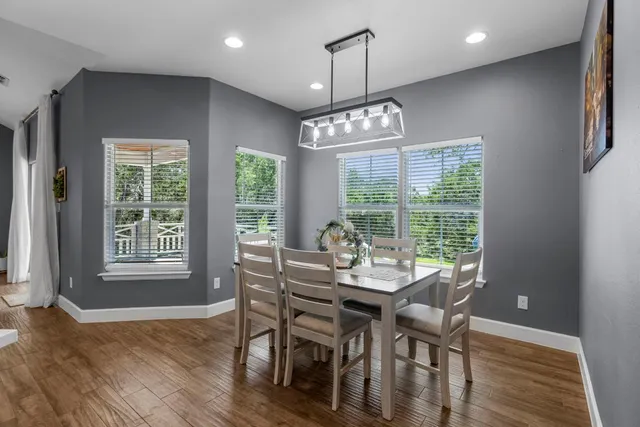 a kitchen with stainless steel appliances kitchen island granite countertop a stove a sink a dining table and chairs with wooden floor