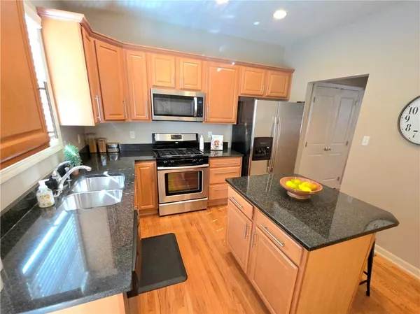 a kitchen with stainless steel appliances granite countertop a stove a refrigerator a sink a stove and white cabinets